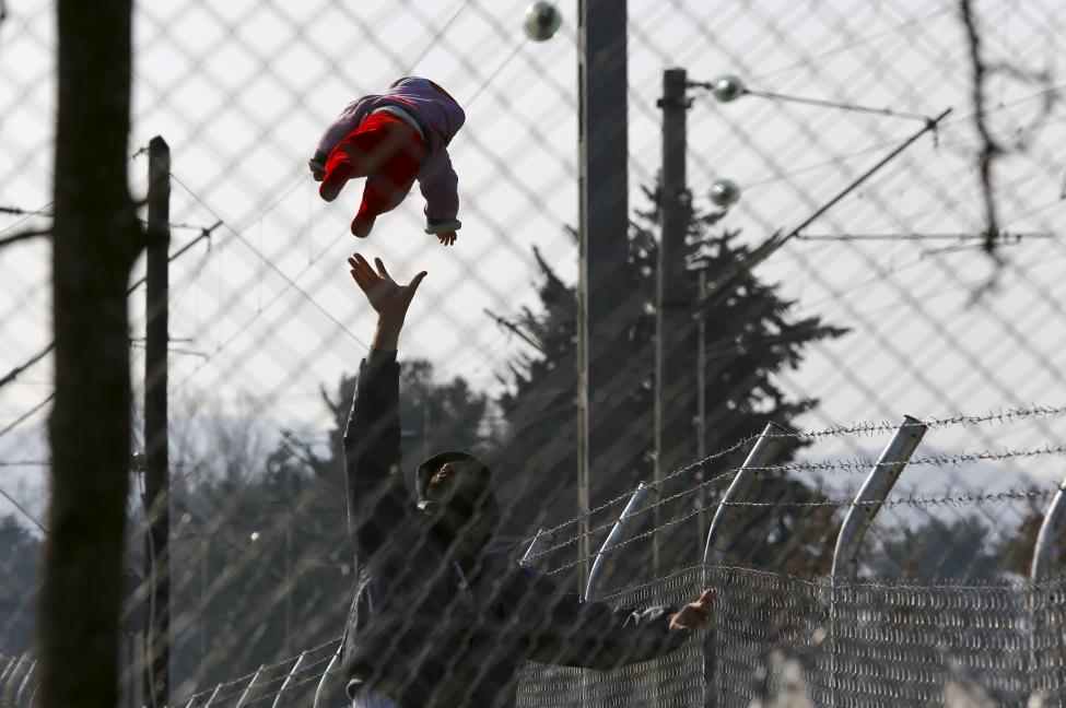 A migrant plays with his baby as they wait to enter Macedonia from Greece near Gevgelija, Macedonia